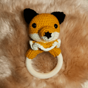 Vauvan virkattu helistin, kettu, oranssi valkoinen pää, mustat korvaat, oranssi valkoinen röyhelö. Puinen rengas