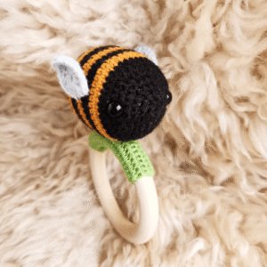 Vauvan virkattu helistin, kimalainen, musta oranssi raidallinen, valkoinen perä, vaaleansiniset siivet. Puinen rengas